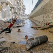 pojat leikkivät pommin repimässä kraaterissa Aleppossa