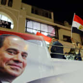 Egyptin presidentin tukijoita auton lavalla, auton kyljessä presidentti Sisin kasvot.
