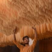 Mies tarkistaa Itä-Pakistanilaisessa tehtaassa nuudelien kuivumista Lahoressa.