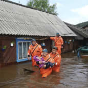 Pelastusmiehet kantavat pientä lasta tulvan keskellä.