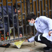 Hengitysmaskiin pukeutunut mies ojentaa asukkaalle lääkettä Kiinan Wuhanissa.