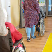 Työntekijät työntävät vanhuksia pyörätuolissa vanhustenkeskuksessa.