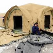 Mies istuu siirrettävän telttasairaalan edustalla Muurmanskissa.