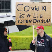 Kuvassa on mielenosoittaja, jonka kyltissä vaaditaan Oregonin osavaltion avaamista.