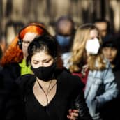 Maski kasvoillaan kulkevia ihmisiä Helsingin keskustassa.