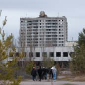 Ihmisjoukko kävelee kohti suurta, neuvostotyylistä rakennusta.