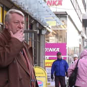 Mies seisoo kadulla ja polttaa tupakkaa.