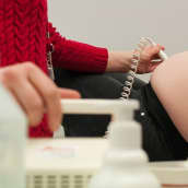 Terveydenhoitaja tutkii odottavan äidin kohtua ultraäänellä.