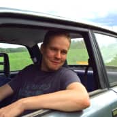 Pekka Holmström istuu autossa ikkuna auki ja käsi ikkunan pielen päällä. 
