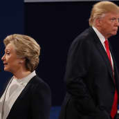 Hillary Clinton ja Donald Trump selin toisiinsa vaaliväittelyn aikana. Mikrofoni on Clintonilla. 