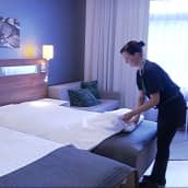 Siivooja petaa sänkyä hotellihuoneessa.