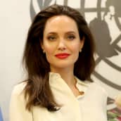 Angelina Jolie puolilähikuvassa, taustalla YK:n logo.