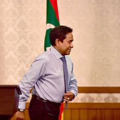 Malediivien vaalit hävinnyt presidentti Abdulla Yameen kävelee pois puhujapöntästä.