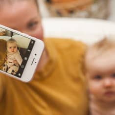 Äiti ottaa kuvaa itsestään ja vauvasta älypuhelimella.