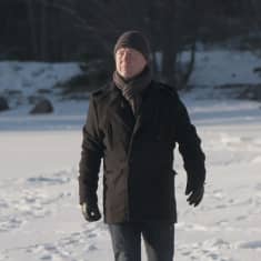 Mies kävelee lumisella rantajäällä.