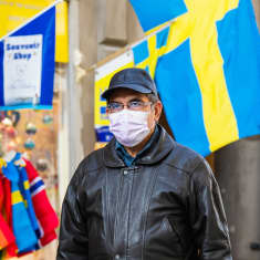 Hengityssuojaan pukeutunut mies kävelee kadulla Tukholmassa.