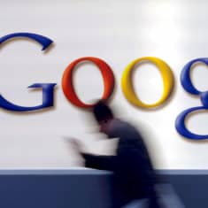 Mies kävelee Googlen logon editse