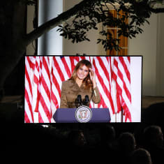 Melania Trump kuvattuna Valkoisen talon puutarhassa sijaitsevan näytön ruudulta..