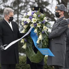 Mies ja nainen sytyttävät kynttilää Hietaniemen hautausmaalla.