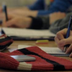 Opiskelijalla puhelin pöydällä oppitunnin aikana.