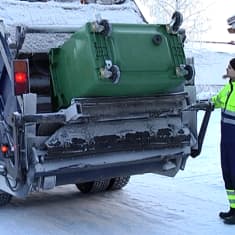 Jäteauton kuljettaja tyhjentää roska-astiaa.