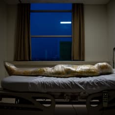 Muovikelmuun kääritty koronan uhri makaa sairaalan sängyllä.