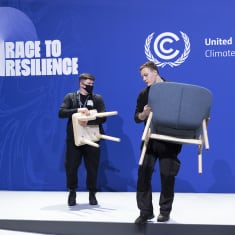 Työntekijät kantavat tuoleja lavalta ilmastokokouksen päätyttyä.