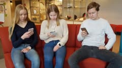 kolme nuorta yhdeksäsluokkalaista kännyköidensä kimpussa