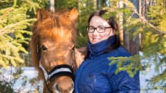 Tiia-Maria Joensuu seisoo metsikössä Mansikka-hevosen vieressä.