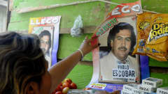 Nainen kiinnittää seinään julistetta huumeparoni Pablo Escobarista.
