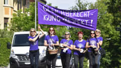Kuusi naista marssii mielenosoitusjulistetta kantaen.