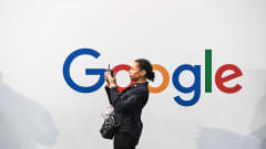 Nainen ottamassa selfietä.  Taustalla olevalla valkoisella seinällä on Googlen logo.