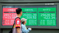 Ohikulkijat katselevat Tokion, Shanghain ja New Yorkin pörssien indeksejä infotauluilta Tokion pörssin edustalla.