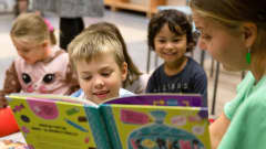 Lapsia lukemassa kirjoja kirjastossa.