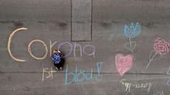 Saksalainen lapsi kirjoittaa väriliiduilla asfalttiin "Korona on tyhmä".