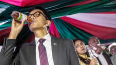 Andry Rajoelina juo yrttiteetä pullon suusta.
