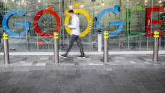 Mies käyttää matkapuhelinta googlen logon edustalla Singaporessa.