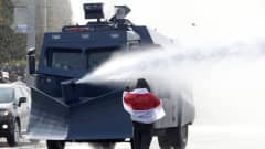 Valkovenäläinen mielenosoittaja uhmaa poliisin vesitykkiautoa.