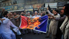 Pakistani people burn a mock of a French flag during a demonstration against French President Macron's comments over Prophet Muhammad caricatures, in Peshawar, Pakisan, 26 October 2020. A group of protestors gathered to protest Macron's comments following the recent beheading of a teacher in France, after he had shown caricatures of the Prophet Muhammad in class. Macron vowed his country would not give up publishing such cartoons. EPA-EFE/ARSHAD ARBAB