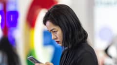 Nainen selaa puhelinta Googlen logon edustalla messuilla Guiyangissa Kiinassa