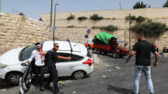 Israelilaine npoliisi osoittaa aseella palestiinalaismiestä.