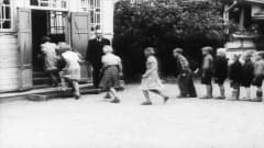 Lapset juoksevat koulurakennukseen sisälle jonossa.