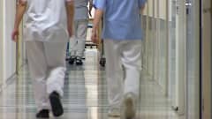 Sairaanhoitajia kävelee keskussairaalan käytävällä.