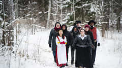 Erilaisia suomalaisia kävelemässä lumista polkua.