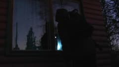 Pimeässä mies kesämökin ikkunan äärellä