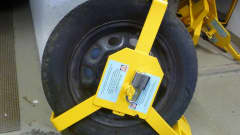 Keltainen rengaslukko kiinnitettynä autonrenkaaseen
