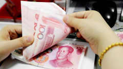 Kiinalainen pankkivirkalija laski rahoja Lianyungangissa.