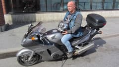 Kuvassa Jouni Takki istuu moottoripyörän satulassa. Kypärä lepää bensiinitankin päällä.