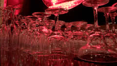 Erilaisia lasisia juomalaseja, kuten konjakki- ja viinilaseja, punaisessa valossa.