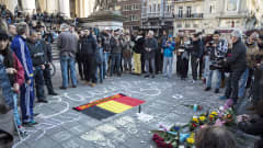 Ihmisiä kokoontuneena maassa olevan Belgian lipun ympärille Brysselissä.